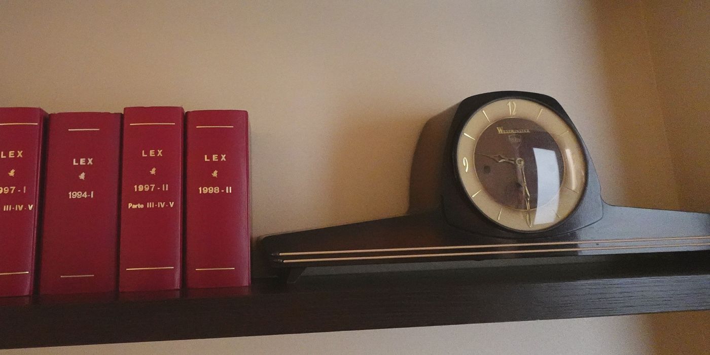 Un orologio da mensola d’epoca accanto ai volumi rossi della raccolta LEX