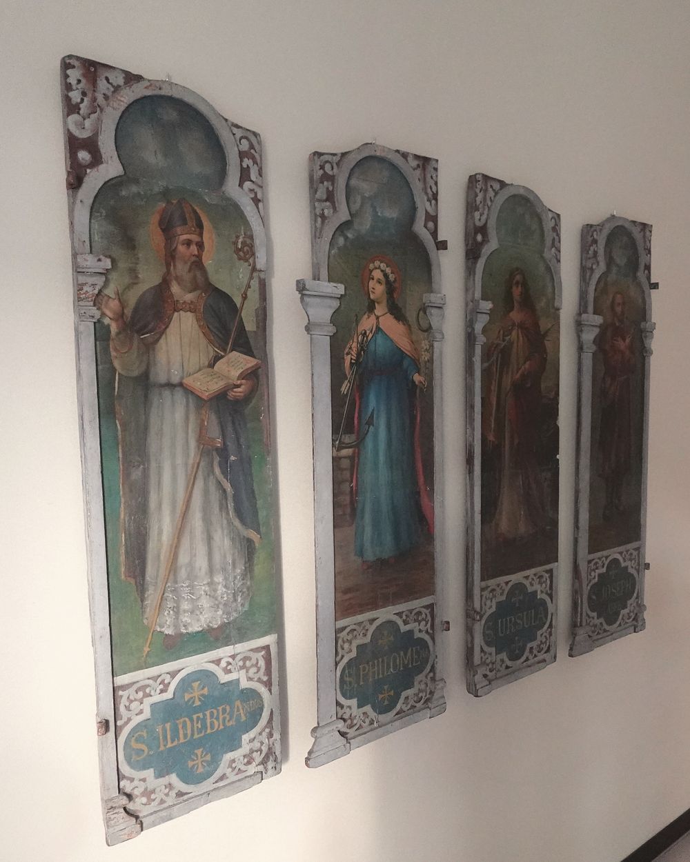 Quattro antiche tavole dipinte con figure di santi appese alla parete della sala